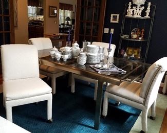 Metal frame dining table. Ends pull out to accommodate the self-storing leaf. Set of 6 white upholstered chairs.