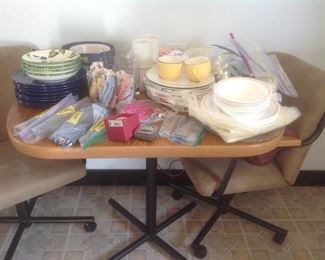 Sets of dishes, flatware and a small kitchen table with chairs