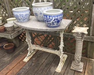 Cast iron garden table base with marble top, assorted planters, cement pedestal
