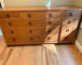 A Stickley 21st Century Mission Collection Triple dresser in cherry.The dresser features ebony inlay on top, chambered posts, painted black accents, and black metal hardware. This is a nine drawer dresser and there is a sliding jewelry tray in the top right drawer