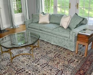 Green damask sofa and one of a pair of glass and brass occasional tables