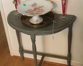 Green end table with beautiful cake plate and red bud vases.