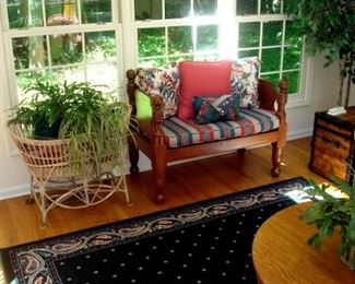 Antique upholstered settee, wicker baby cradle and plants.