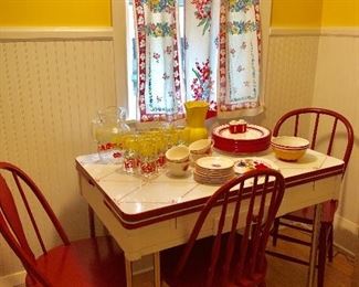 Vintage kitchen enamel top (printed) table and 3 red chairs.   Red and white dishes and glassware