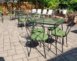 Three metal and glass top square patio tables each photographed with a set of four chairs