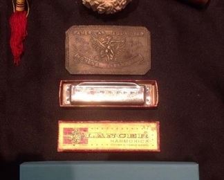 Family Room-Case: a Chinese wooden ball puzzle key ring; a Chinese carved ball-in-ball-in ball puzzle; a vintage Van Cort side viewer; an "American Equality-Votes for Women-Free Speech-Women's Liberation" belt buckle; a vintage LANCER harmonica; and an empty TIFFANY & CO. box.