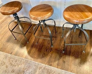 Three wood/metal stools that can be raised or lowered by turning seat