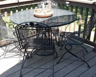 Wrought iron patio table and four spring action chairs