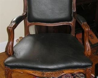 There are two of these black leather armchairs with footstools