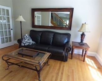 Leather Sofa with Nail Trim. Large beveled mirror can be used horizontally on wall or vertically leaning agains wall. Glass, wrought iron and wood coffee table. Side table and Floor Lamp and table lamp