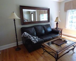 Leather Sofa with Nail Trim. Large beveled mirror can be used horizontally on wall or vertically leaning agains wall. Glass, wrought iron and wood coffee table. Side table and Floor Lamp and table lamp