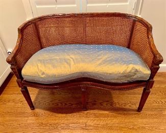 Theodore Alexander cane backed settee with silk cushion.