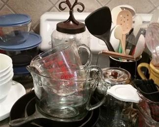 Cast iron skillets, selection of glass measuring cups, tea kettle, canister, kitchen utensils 