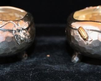 A rare pair of Tiffany antique sterling and mixed metal hammered Japanese style salt cellars with spot hammered surfaces and applied copper details.