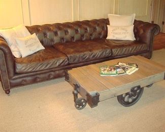 Family Room: The RESTORATION HARDWARE "Kensington" sofa has a Chesterfield-style with tufted back, rolled arms, nail head trim and casters. It measures 9' 8." The RESTORATION HARDWARE railroad cart coffee table is wood with iron wheels and hardware. The pillows and railroad books are separately priced.