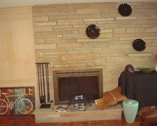 Family Room: A bicycle print, heavy iron fireplace tools, and other décor are shown near and on the hearth.