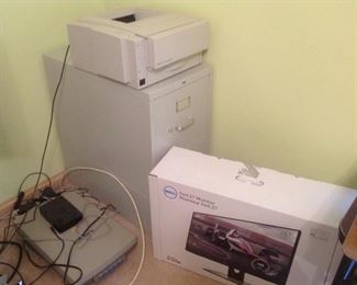 Bedroom #1: A Hewlett-Packard laser jet 6MP printer rests on a file cabinet that is not for sale. On the left is a Hewlett-Packard scan jet 6300C; on the right is a new still-in-the-box DELL 27" monitor.