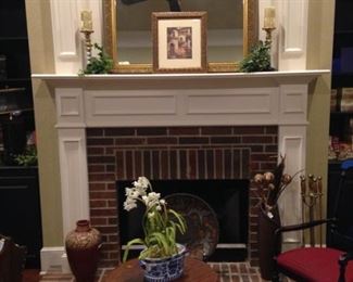 The formal living room mantel houses a beautiful gold framed mirror.