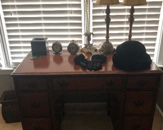 Desk, fraternal twin clocks and two lamps looking at themselves in a funhouse mirror.