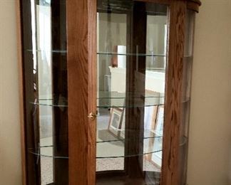 Oak lighted curved glass china cabinet has claw feet