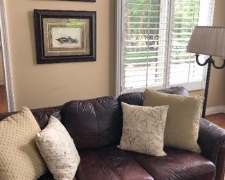 Leather couch, floor lamp and framed prints