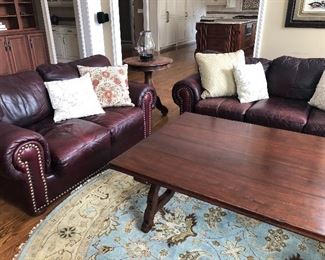 Leather couch and love seat, large coffee table and round area rug, and side table with iron hurricane candle holder