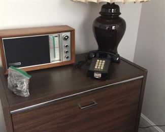 Two-drawer file cabinet, vintage radio, telephone and lamp.