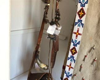 Detail of carved powder horns, hunting pouch, bear claw necklace and Plains Indian scarf with bead work and tin crimps.