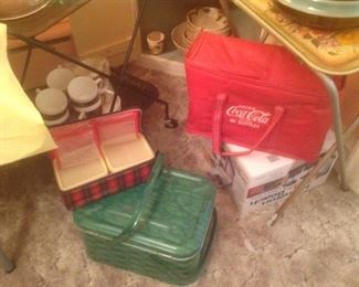 Metal picnic basket, Coca Cola soft carrier and vintage plaid sandwich carrier. Behind it is a luncheon set.