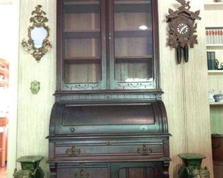 Antique mahogany desk/display cabinet with wavy glass and carved bonnet, German cuckoo clock, pair of green terra cotta elephants. 
