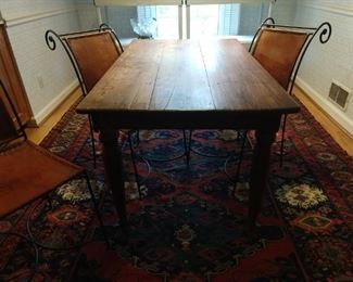 Small wooden farm table, with three wrought iron/leather side chairs.