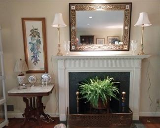 One of two fireplaces in the house that needa good mirror, gold candlestick lamps, antique English fire bumper and andirons, a Victorian marble-topped table, strewn with vintage English silverplated petit fours servers. The mahogany plant stand has a metal liner and thriving Boston fern.