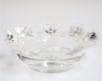 Lot 17: A Lalique Crystal "Saint Nicholas" Ashtray.  Small bowl with repetitive mask motif.  Etched signature "Lalique France".  Minor surface scratches at the underside.  4 1/4" diameter.