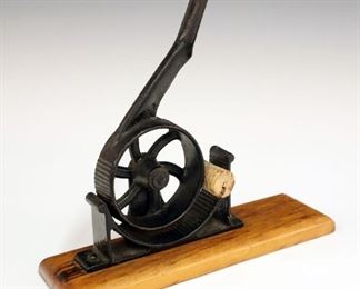 Lot 29: A Turn of the Century Cork Tapering Machine.  Mechanical, cast iron with wood base.  Wear.  10" long.