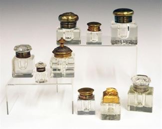 Lot 41: A Collection of Nine Inkwells.  Crystal inkwells with varying types of covers.  Some indentations to covers, wear, and slight nicks.  From 1 1/4" to 3" high.