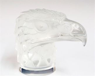 Lot 13: A Lalique Crystal Car Mascot.  Eagle form hood ornament.  Etched signature "Lalique France" with "Made in France" label at underside.  Very minor wear, condition appears to be good.  4 1/2" high.  