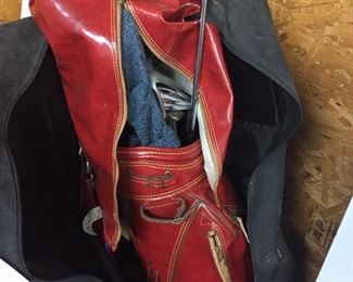 Hogan golf clubs in a red leather type bag with traveling carry case.