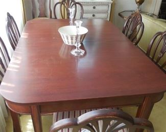 Mahogany dining table with six very nice chairs with upholstered seats.