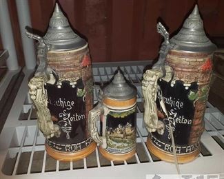 6618:
3 beer steins
BEER STEINS!!!!!!! Romanesque style beer steins, each in hard stone ceramic with tin metal flip hats and oil-rub powder ceramic painted markings. The smallest features pictorials of Vianden Castle and Deiwelselter stone landmark of Luxembourg. The other two are German beer stein Cherusker 1 liter tankard/beer mug. This is handmade German pottery with “ruh hast du nur in der schenken” and “unruhige zeiten” embossed by hand. Has grey tin metal lid stamped “made in West Germany” with raised relief, colors depicting knights charging into a village depicting real life scenes. In beautiful condition!! Tallest is approx. 11" tall and the shortest is 7" tall
