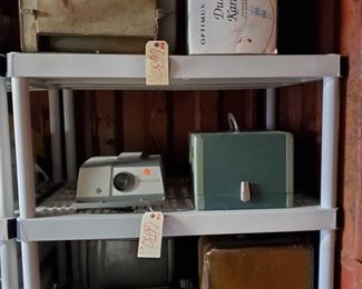 6630: Vintage TV, Radio, Typewriter, Projectors and Cases, Car Cooler and Karaoke System
LOTS of vintage things to see in this lot!
*a Samsung portable TV AM/FM radio model BT-123AJ (1984), AC 120 volts, 60Hz, 11 watts-DC12 volts 6 watts. Includes manual and cords.
*a medium sized (appx 20”) television
*a vintage brown leatherette typewriter case
*a vintage Sears Citation 1960’s portable typewriter with original case. This is a cream-colored model with gray interior, black case. Made in the 1960’s still in good condition.
*a vintage AirEquipt 135 35mm 2x2 slide projector with remote changer
*a vintage Argus 300 automatic slide projector with slide changer in box – great condition
*a Polar Breeze automatic car cooler (circa 1940’s)
*an Optimus dual-cassette karaoke system, all in one portable entertainment center in box