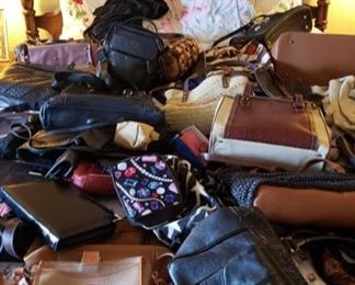 8700:
Lot of Purses and handbags
Featuring a large lot of assorted women’s purses in various styles, colors, and materials. Many leather hand strap and shoulder strap styles, from everyday purses to fancy handbags – this is a nice mixed collection.