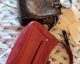 8709:
2 Coach Handbags
Shown here are two Coach purses, one is new with plastic and tags! A black purse with black handles model #6825 and the other is a red leather handbag with front zippered compartment and top zippered closure.