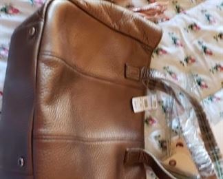 8710:
2 Handbags
This lot features a nice brown leather Talbots handbag with tag still on. Another small handbag shown here is an unusual handheld item with a pearl white body and camel leather trim.