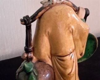 Antique Chinese Mud Man figurine, 10", carrying coin and fruit. Attached via bolt to brass base.