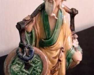 Antique Chinese Mud Man figurine, 10", carrying coin and fruit. Attached via bolt to brass base.