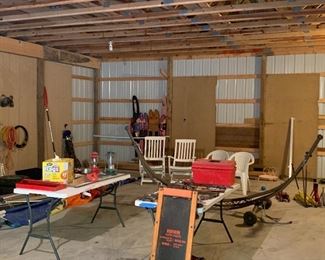 Pole barn is filled with various items including lanterns, out door chairs, ladders, creeper, skis, lawn tools etc..