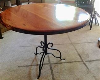 Beautiful Round Wood Table with Wrought Iron Base The table top has a very thick coat of polyurethane.