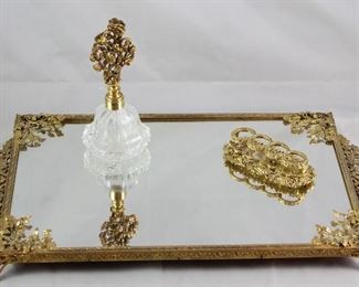 Hollywood Regency Mid Century Gold Plated Rectangular Vanity Mirror, Crystal Perfume with Gold Plated Floral Glass Dauber Stopper and “The Buckles” Lipstick Holder.
