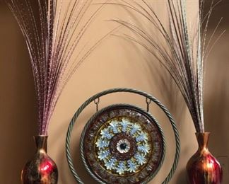 These are two good size vases filled with artificial I-don't-know-what, flanking a gong-shaped neat decoration piece.