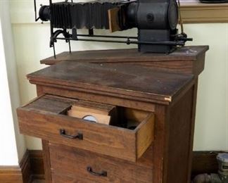 The M.C. Lilley And Co. Antique Electric Slide Projectors With Rolling Wood Projector Table Includes Antique Wood Slides In Top Drawer 40" X 34"X 21
